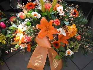 Buntes Trauergesteck aus Lilien, Gerbera und Rosen mit Schleife