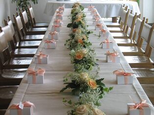 Lange Festtafel mit einer Girlande aus Rosen und Grün sowie Gastgeschenken