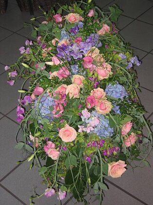 Trauergesteck aus rosafarbenen Rosen und blauen Blüten