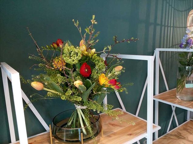 Bunter Frühlingsstrauß mit Tulpen in einer Glasvase im Ladengeschäft