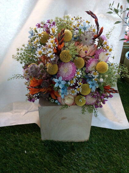 Sommerwiesenstrauß mit Wiesenblumen und Gräsern in einer weißen Vase