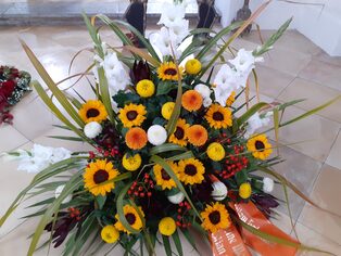 Trauergesteck aus Sonnenblumen, Gräsern und Beerenzweigen