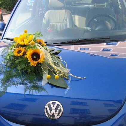 Blauer VW mit Autoschmuck aus Sonnenblumen und Gräsern