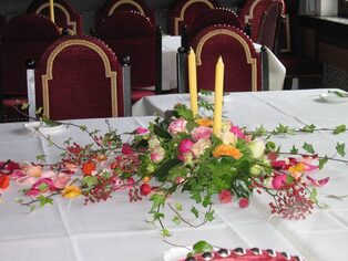 Festtafel mit hohen Kerzen und einer bunten Blumengirlande