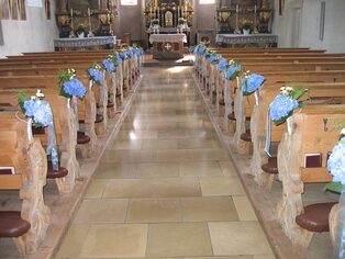 Mittelgang einer Kirche mit blau-weißem Bankschmuck zur Hochzeit