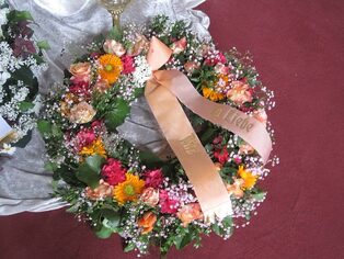 Bunter Trauerkranz aus Rosen und Nelken mit einer Trauerschleife