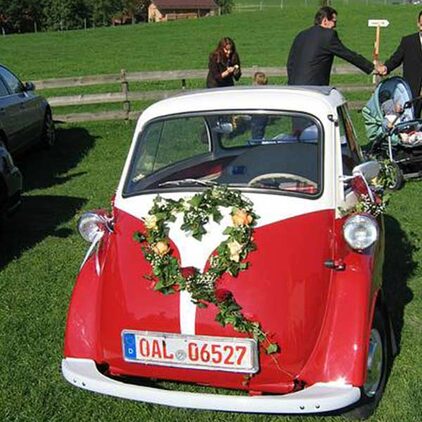 Herz aus Efeu und Blüten auf einer roten BMW Isetta