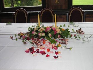 Festtafel mit einem langen Blumengesteck und hohen Kerzen