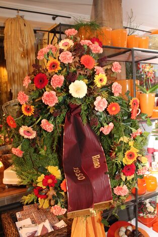 Trauerkranz aus orangefarbenen Rosen und Nelken mit Schleife im Ladengeschäft