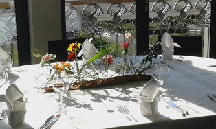 Gedeckter Tisch mit filigranem Gesteck aus Gräsern und Blüten