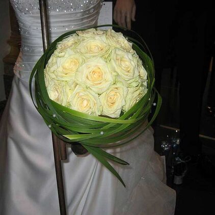 Runder Brautstrauß aus cremefarbenen Rosen mit einer Manschette aus Gras