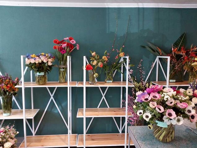 Fertige Blumensträuße auf weißen Regalen im Ladengeschäft