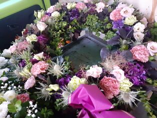 Trauerkranz aus violetten und rosafarbenen Blüten mit Schleife