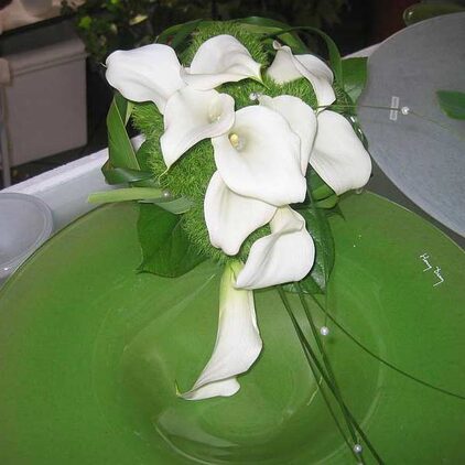 Brautstrauß aus weißen Callas auf einer grünen Schale