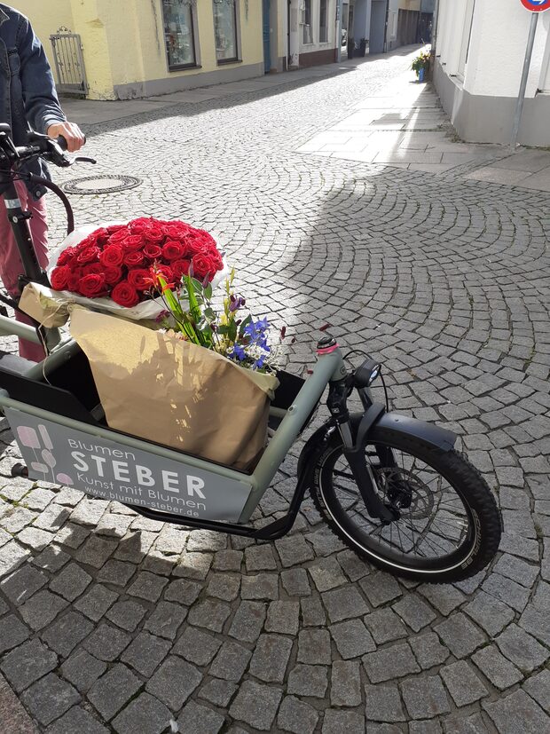 Lastenrad von Blumen Steber mit einem Strauß roter Blumen in der Füssener Altstadt