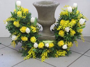Steinurne mit einem Kranz aus gelben und weißen Frühlingsblumen
