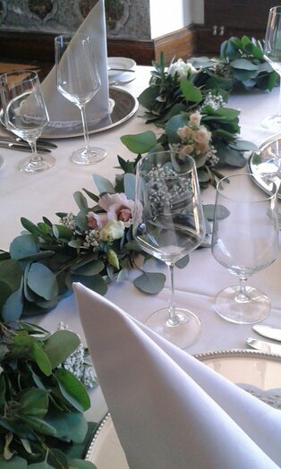 Tischgirlande aus Eukalyptus und weißen Blüten auf festlicher Tafel
