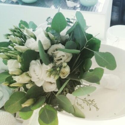 Brautstrauß aus weißen Blüten und Eukalyptus vor der Hochzeitstorte