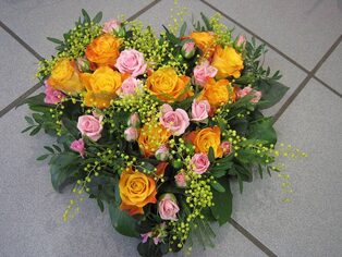 Herzförmiges Trauergesteck aus gelben und rosafarbenen Rosen