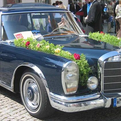 Mercedes-Oldtimer mit einer Girlande aus Grün und Blüten