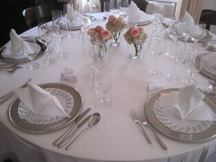 Runder Tisch mit kleinen Vasen voller Rosen und gefalteten Servietten