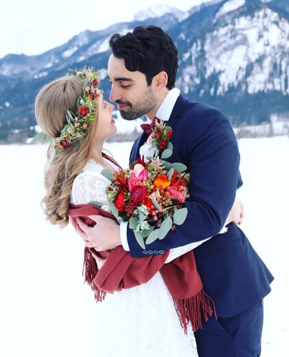 Brautpaar am winterlichen See, die Braut mit Blumenkranz und Winterstrauß